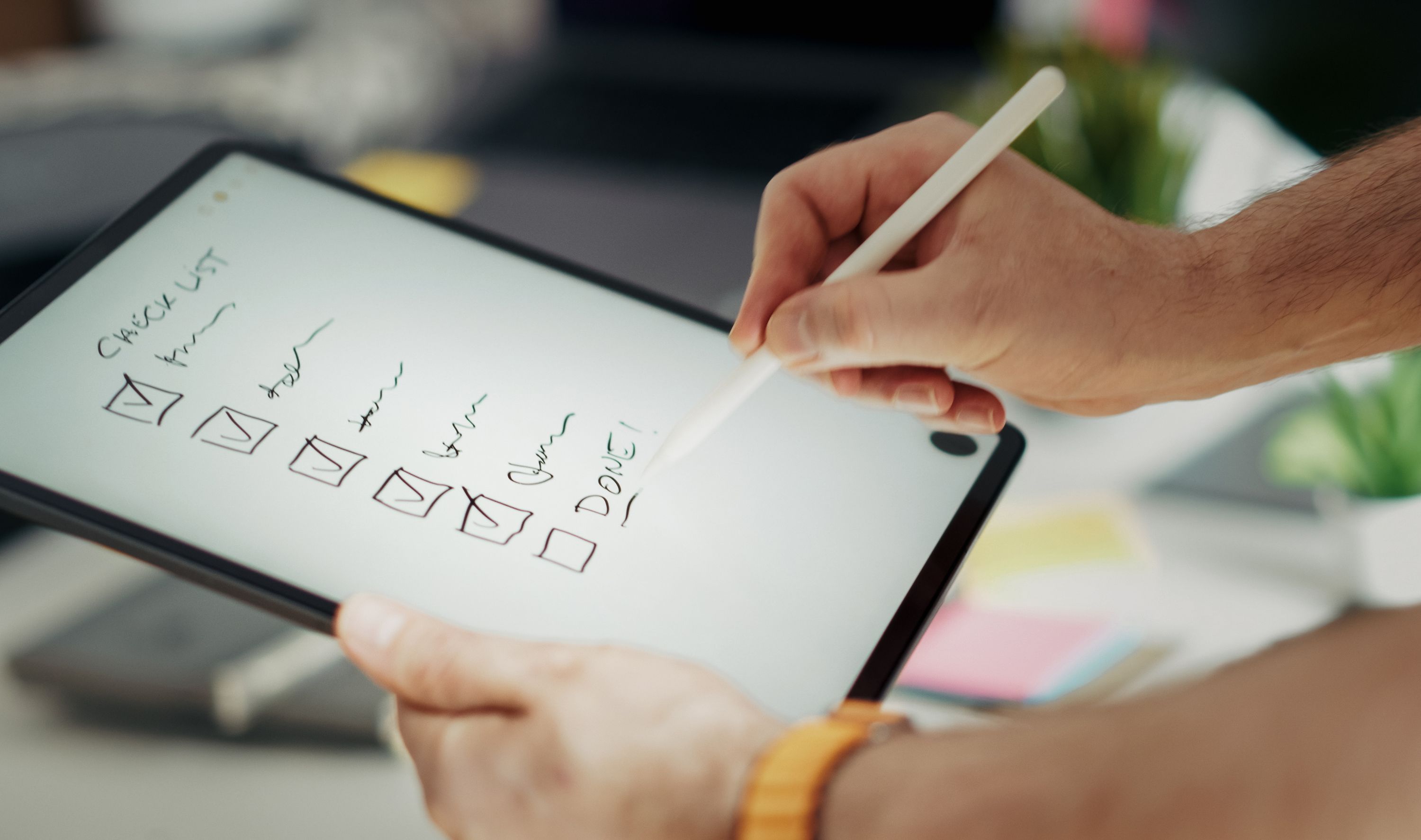 Mão marcando itens de um checklist digital em um tablet, representando processo escrito antes de ser automatizado. Foto de Jakub Zerdzicki via Pexels